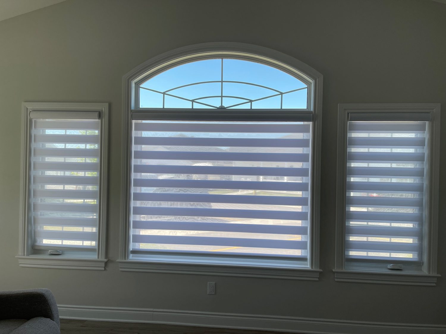 Zebra shades raised to show the view through an arched window