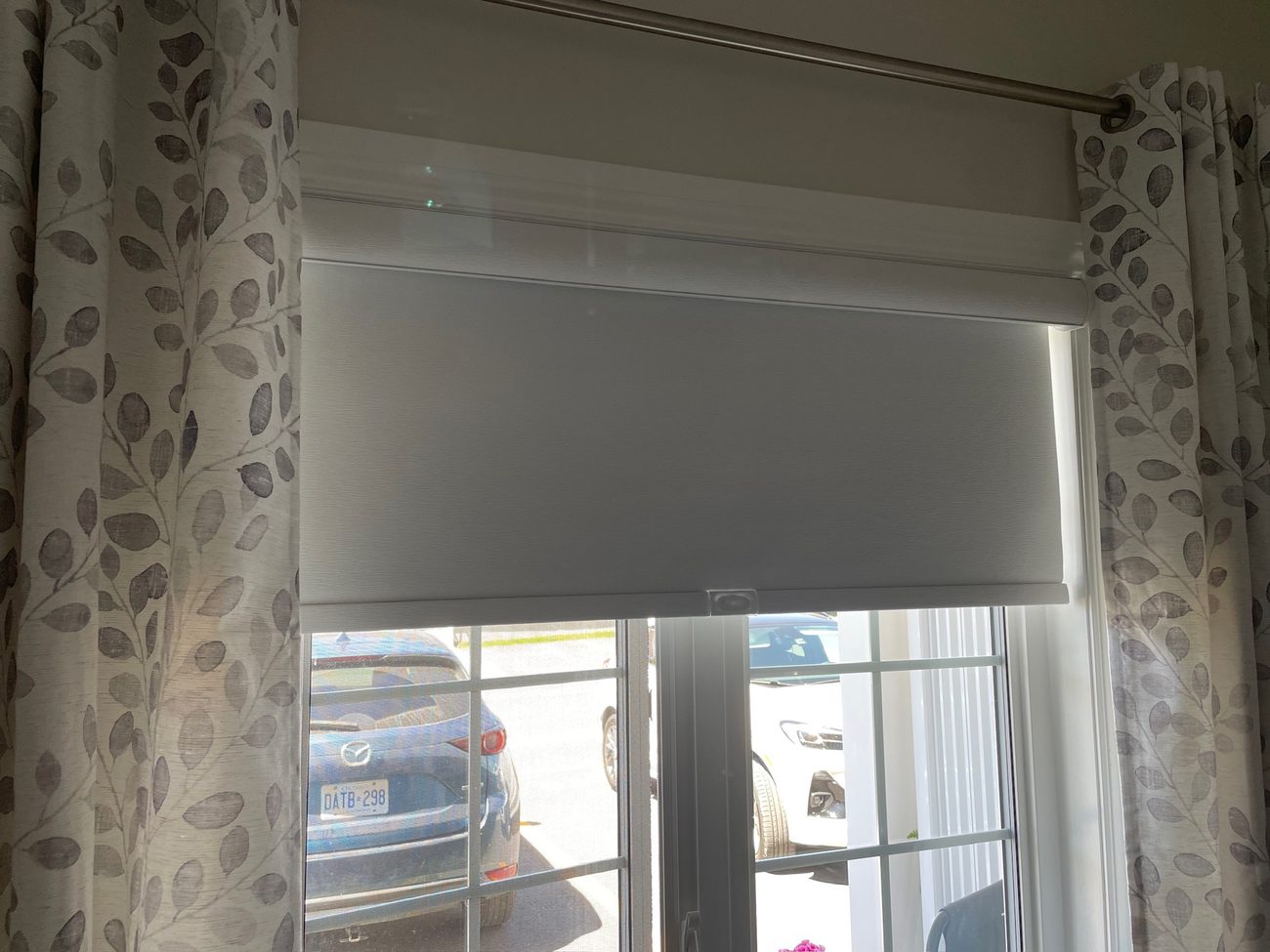 Roller shade over a patio door with patterned curtains